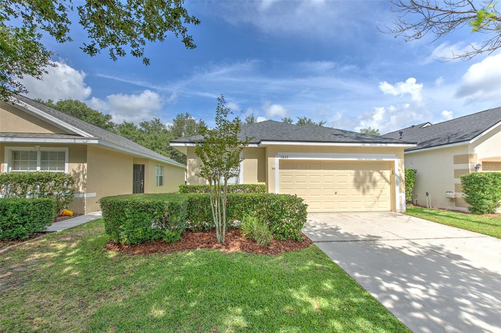 A single-story house with a beige exterior, a two-car garage, and a manicured front lawn — 5843 WRENWATER, LITHIA, FL