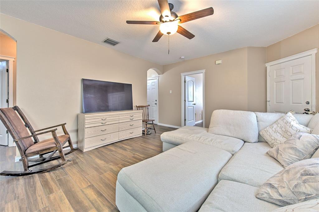 A living room features a sectional sofa, a rocking chair, and a television on a dresser — 5843 WRENWATER, LITHIA, FL