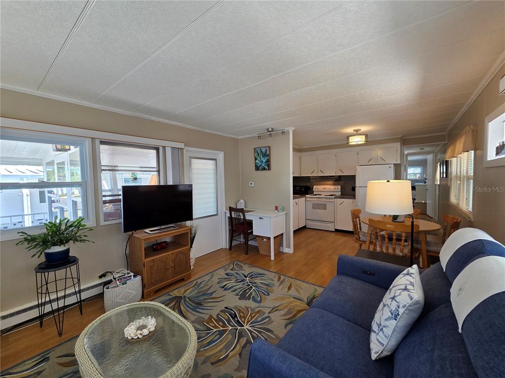 A living room with a blue sofa, television, and an adjacent kitchen with white cabinets — 4333 72ND STREET N UNIT 80, ST PETERSBURG, FL