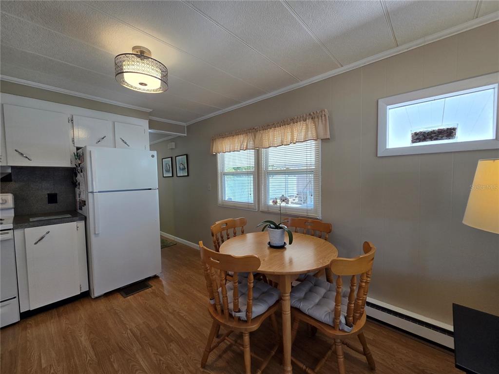 A kitchen and dining area with white cabinets, a refrigerator, and a round wooden table — 4333 72ND STREET N UNIT 80, ST PETERSBURG, FL