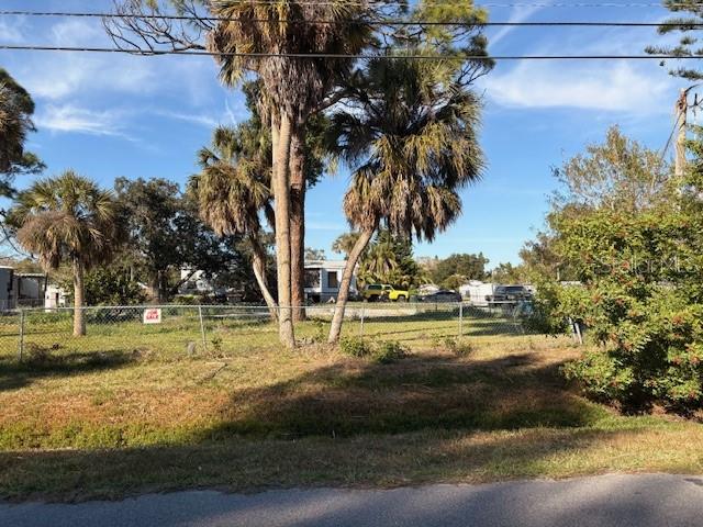 A vacant, grassy lot with palm trees is enclosed by a chain-link fence — 1431 COLONIA LANE E, NOKOMIS, FL