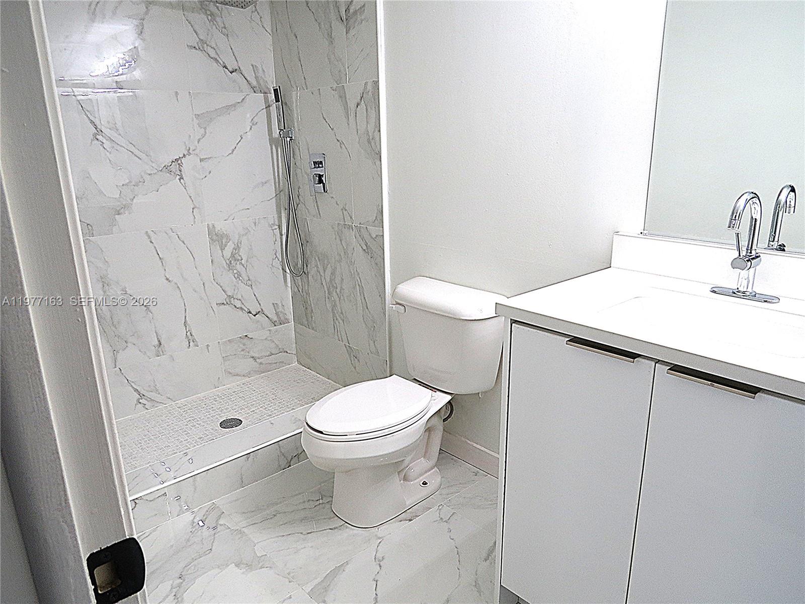 A bathroom features a walk-in shower with marble-look tile, a toilet, and a vanity — 3591 Inverrary Dr # 203, Lauderhill FL 33319, LAUDERHILL, FL