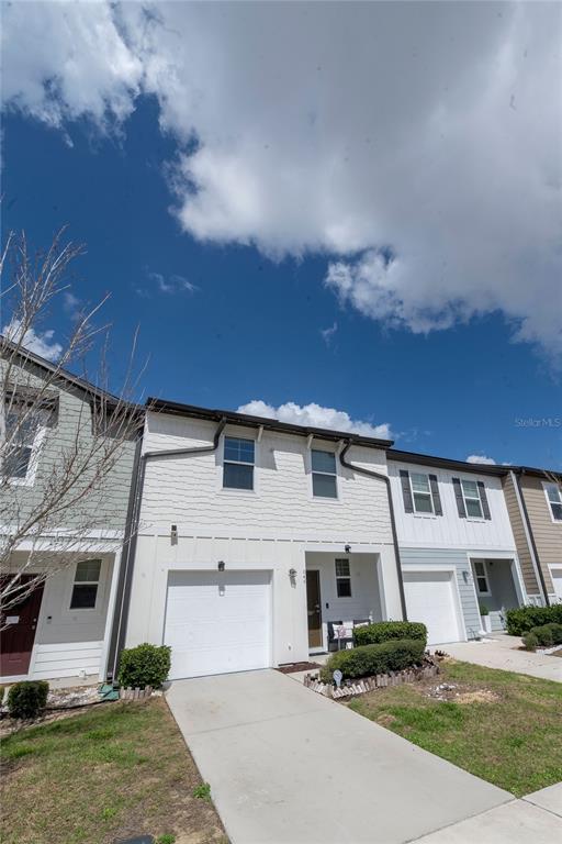 A two-story townhouse with a white garage, light-colored siding, and a concrete driveway — 844 GRANDIN STREET, DAVENPORT, FL