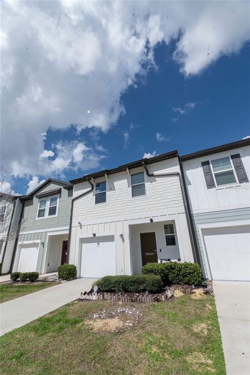 A row of modern townhouses features white siding, attached garages, and small front landscaping beds — 844 GRANDIN STREET, DAVENPORT, FL