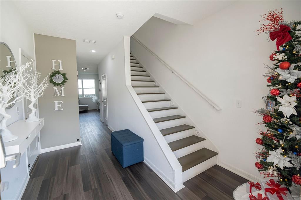 An entryway features wood-look flooring, a staircase with dark treads, and a decorated Christmas tree — 844 GRANDIN STREET, DAVENPORT, FL