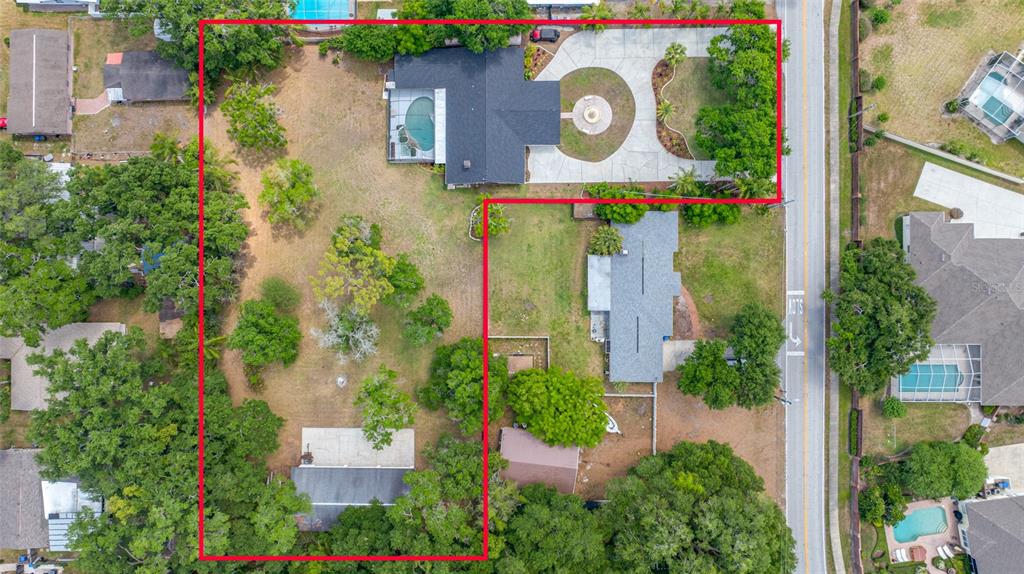 Aerial view of a residential property featuring two houses, a pool, and a large yard — 15314 LAKE MAGDALENE BOULEVARD, TAMPA, FL