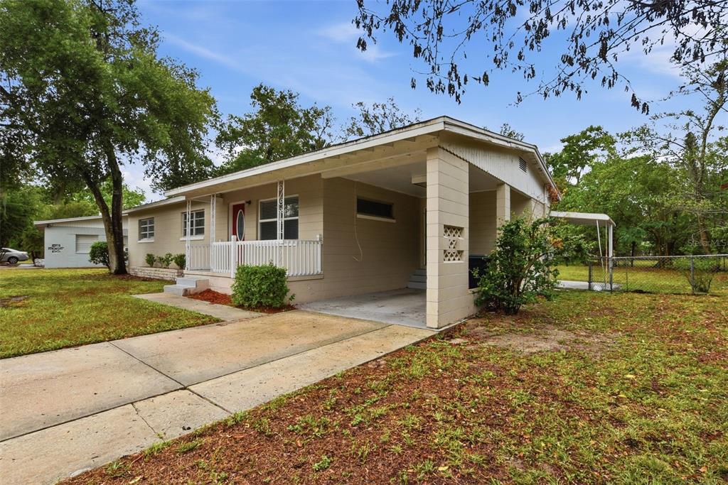 A tan single-story house features a concrete driveway, a front porch, and an attached carport — 5714 LEJEUNE DRIVE, ORLANDO, FL