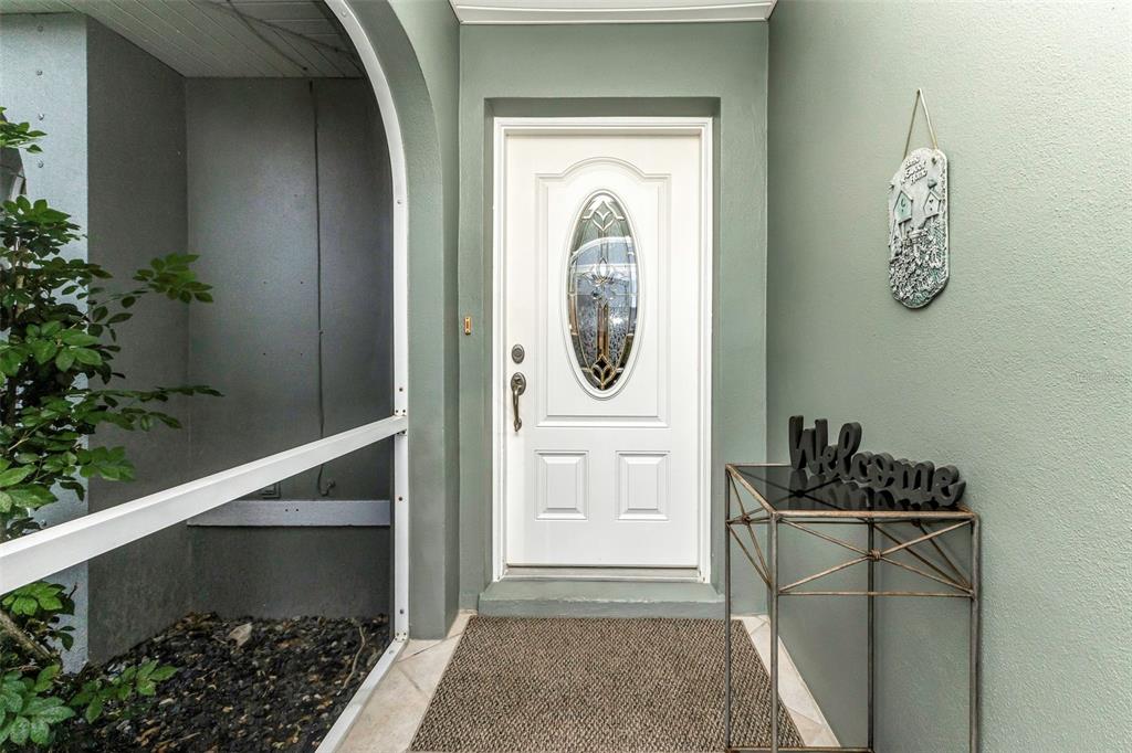 A white front door with an oval glass insert sits in a sage green entryway — 73 MANIZAKS AVENUE, PUNTA GORDA, FL