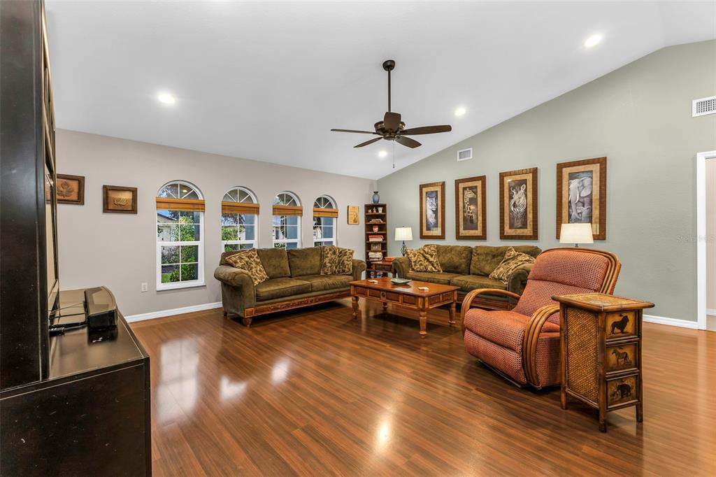 A living room with wood floors, two sofas, an armchair, and arched windows — 73 MANIZAKS AVENUE, PUNTA GORDA, FL