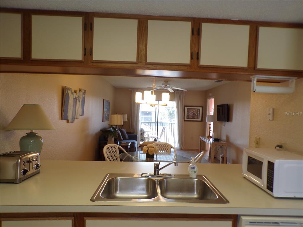 A kitchen sink and counter overlook a living and dining area with a balcony view — 4016 OAKVIEW DRIVE UNIT J9, PORT CHARLOTTE, FL