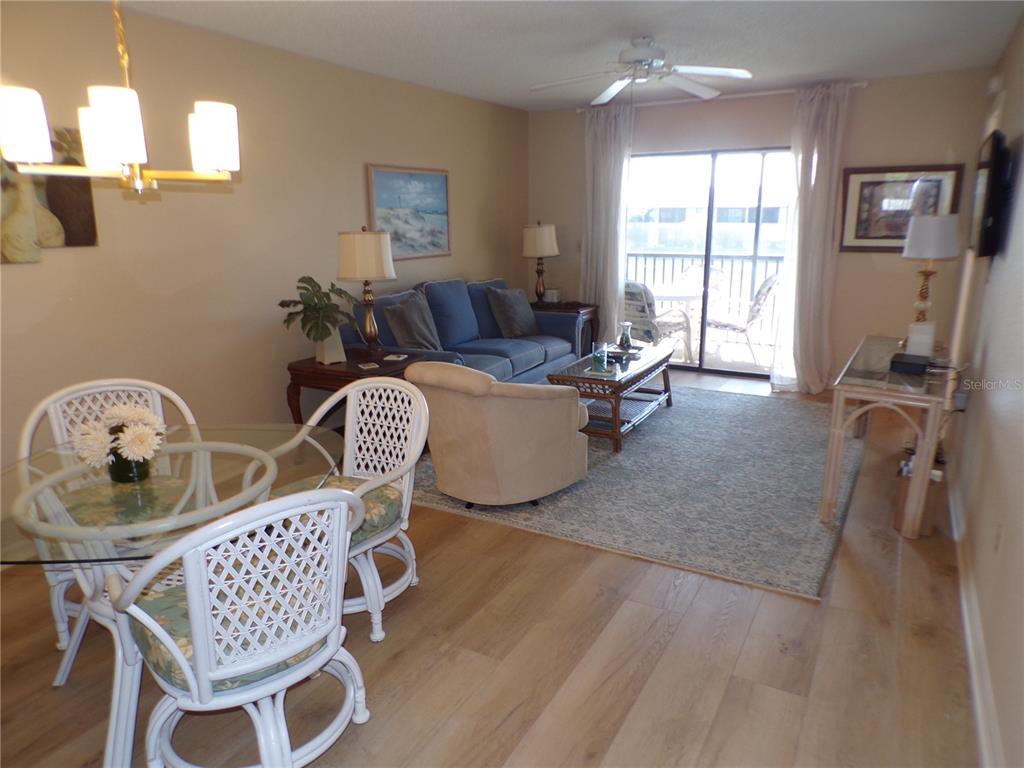A living and dining area features light wood flooring, a blue sofa, and white furniture — 4016 OAKVIEW DRIVE UNIT J9, PORT CHARLOTTE, FL