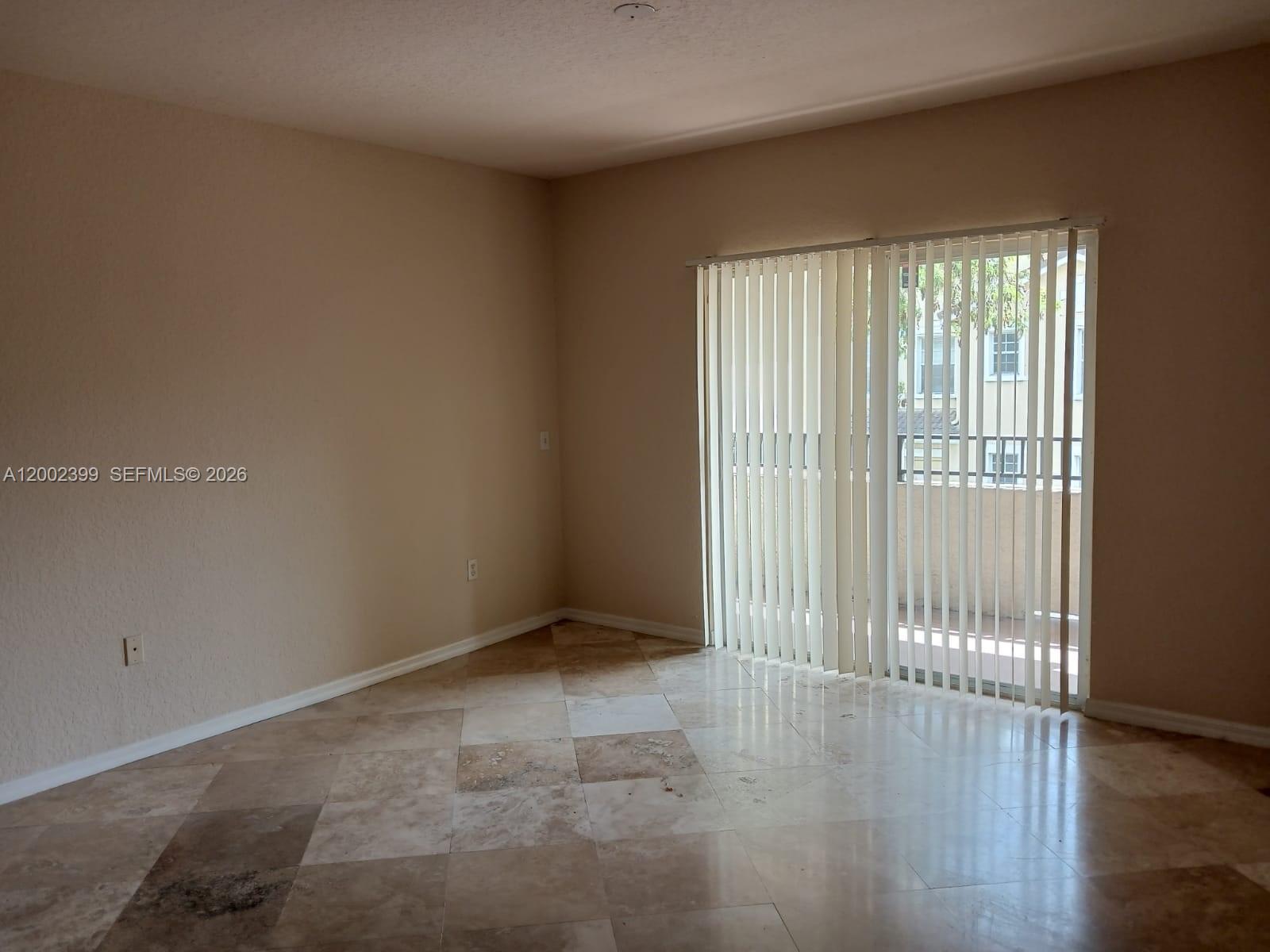 An empty room features beige walls, tile flooring, and a sliding glass door with blinds — NORTH LAUDERDALE, FL