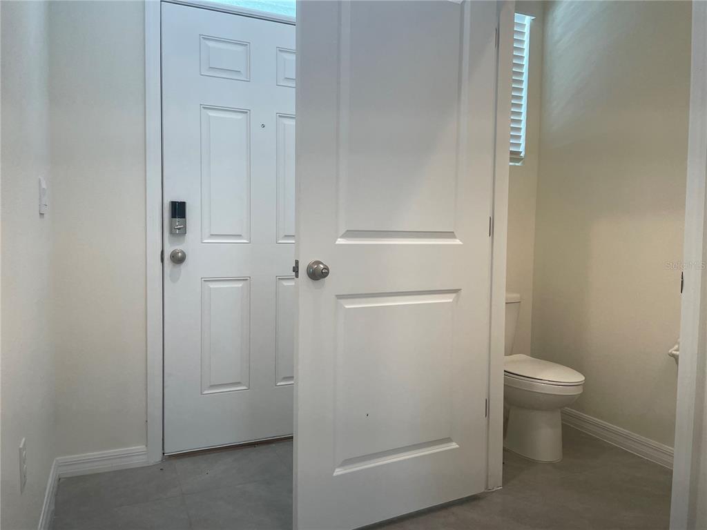 A white door opens to reveal a small bathroom with a toilet and tiled floor — 11127 CRESCENT DEER DRIVE, LAND O LAKES, FL