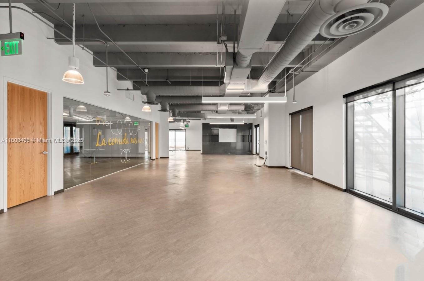 An empty office space features exposed industrial ceilings, glass partitions, and light-colored flooring — 2020 Ponce De Leon Blvd, Coral Gables FL 33134, CORAL GABLES, FL