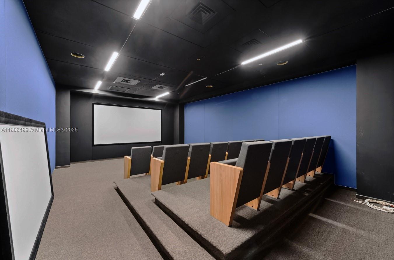 This home theater features tiered seating, a large projection screen, and blue accent walls — 2020 Ponce De Leon Blvd, Coral Gables FL 33134, CORAL GABLES, FL
