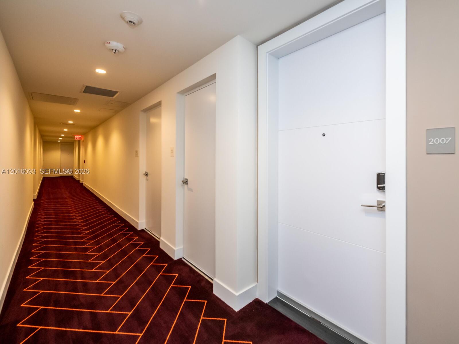 A hallway features dark patterned carpeting, white walls, and several white doors — 2000 S Metropica Way # 2007, Sunrise FL 33323, SUNRISE, FL
