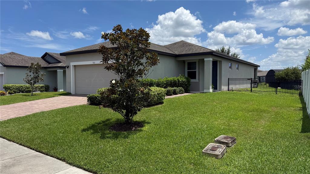 A single-story house with a beige exterior, a two-car garage, and a landscaped front yard — 722 LADYFISH LN, NEW SMYRNA BEACH, FL