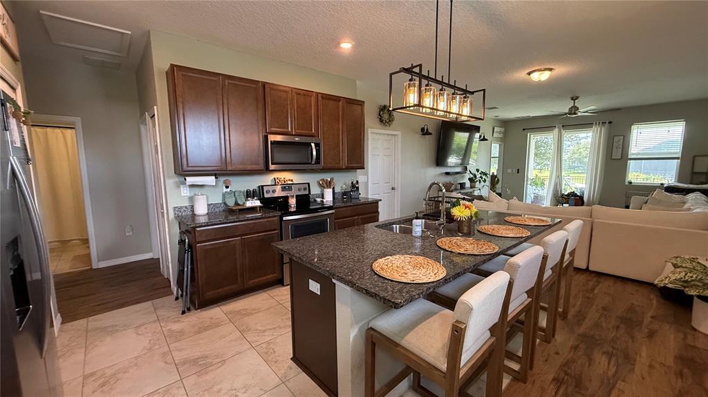 A kitchen with dark wood cabinets, granite countertops, and an island with bar seating — 722 LADYFISH LN, NEW SMYRNA BEACH, FL