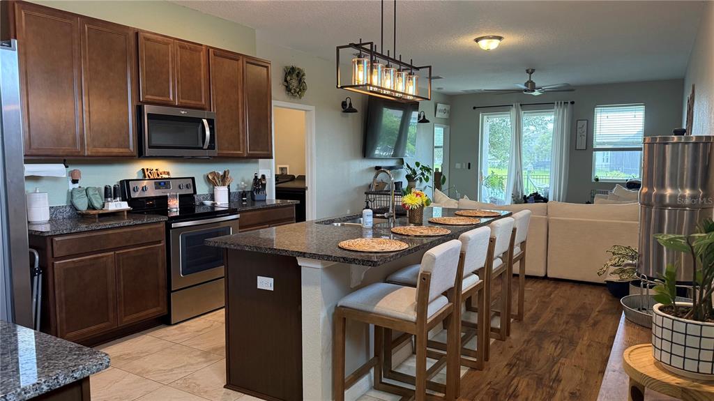 A kitchen with dark wood cabinets, granite countertops, and an island with bar seating — 722 LADYFISH LN, NEW SMYRNA BEACH, FL