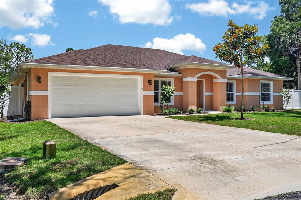 A single-story peach-colored house with a two-car garage and a concrete driveway — 10 PRINCESS MARI PLACE, PALM COAST, FL