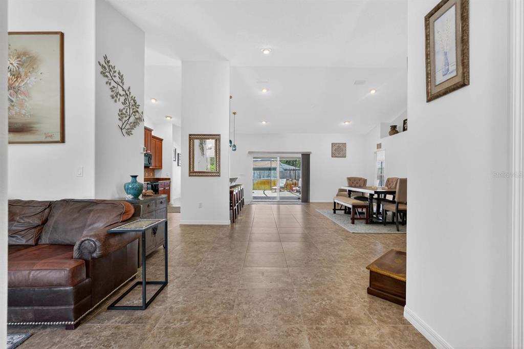 A view from a hallway into an open-concept living area with tile flooring and furniture — 10 PRINCESS MARI PLACE, PALM COAST, FL