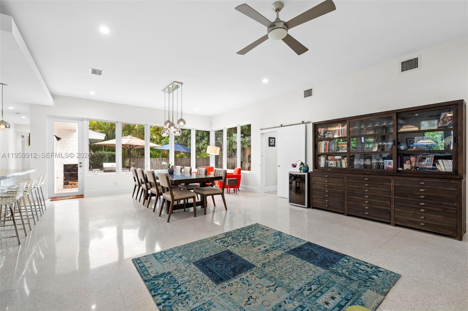 A bright dining room features a large wooden hutch, a glass table, and tile flooring — 4595 N Jefferson Ave, Miami Beach FL 33140, MIAMI BEACH, FL