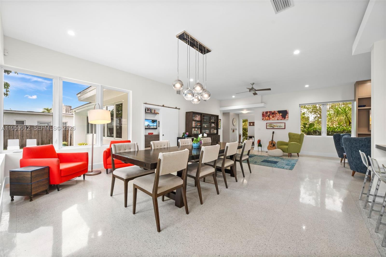 A bright dining room features a long wooden table, modern light fixture, and tiled floors — 4595 N Jefferson Ave, Miami Beach FL 33140, MIAMI BEACH, FL
