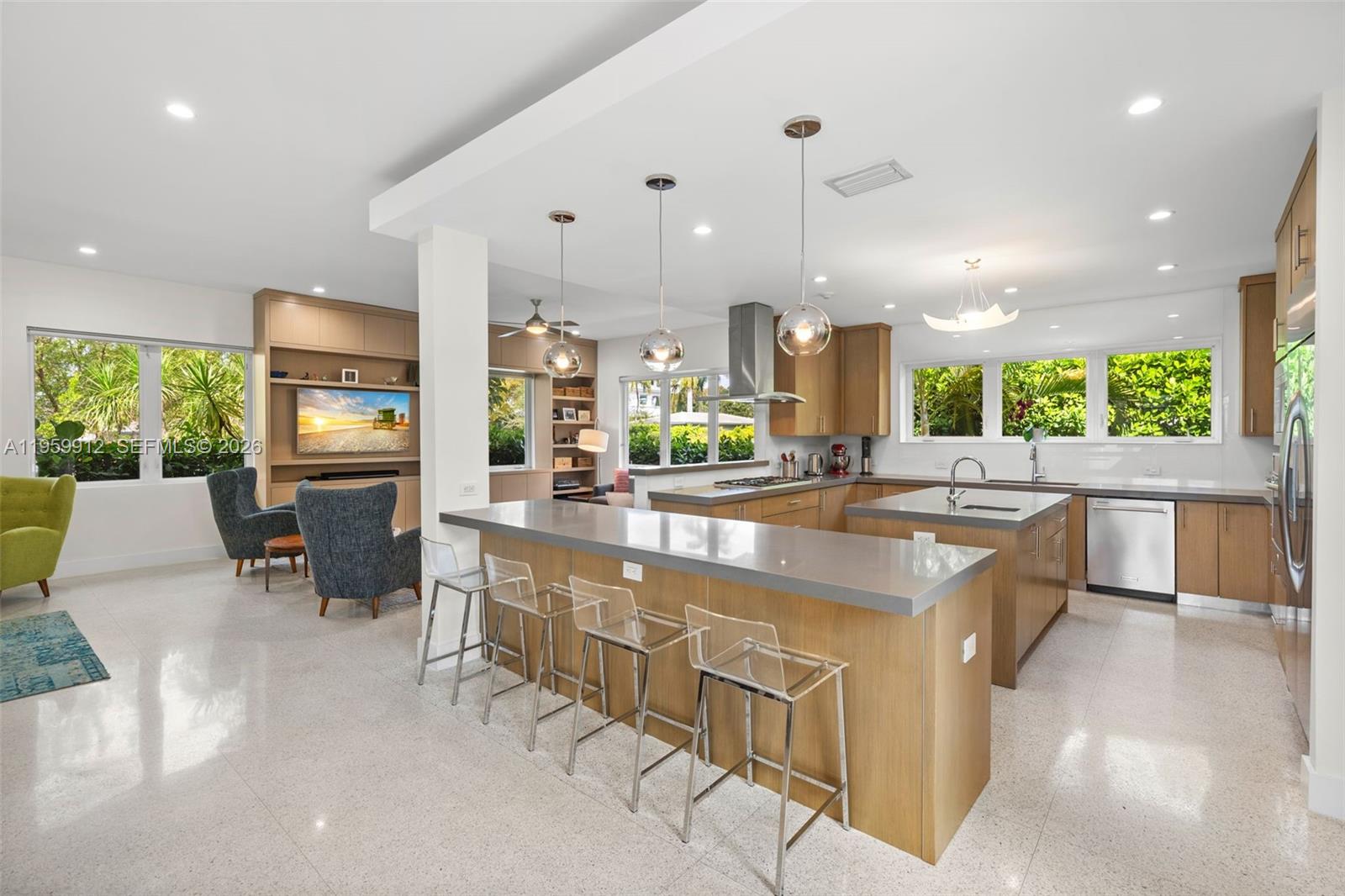 A modern kitchen features a large island with bar seating, wood cabinetry, and tile flooring — 4595 N Jefferson Ave, Miami Beach FL 33140, MIAMI BEACH, FL