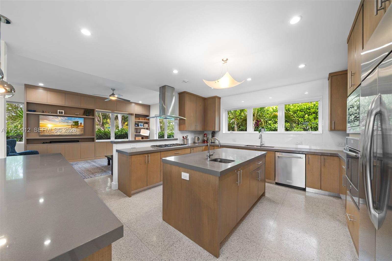 A modern kitchen features wood cabinetry, gray countertops, a central island, and stainless steel appliances — 4595 N Jefferson Ave, Miami Beach FL 33140, MIAMI BEACH, FL