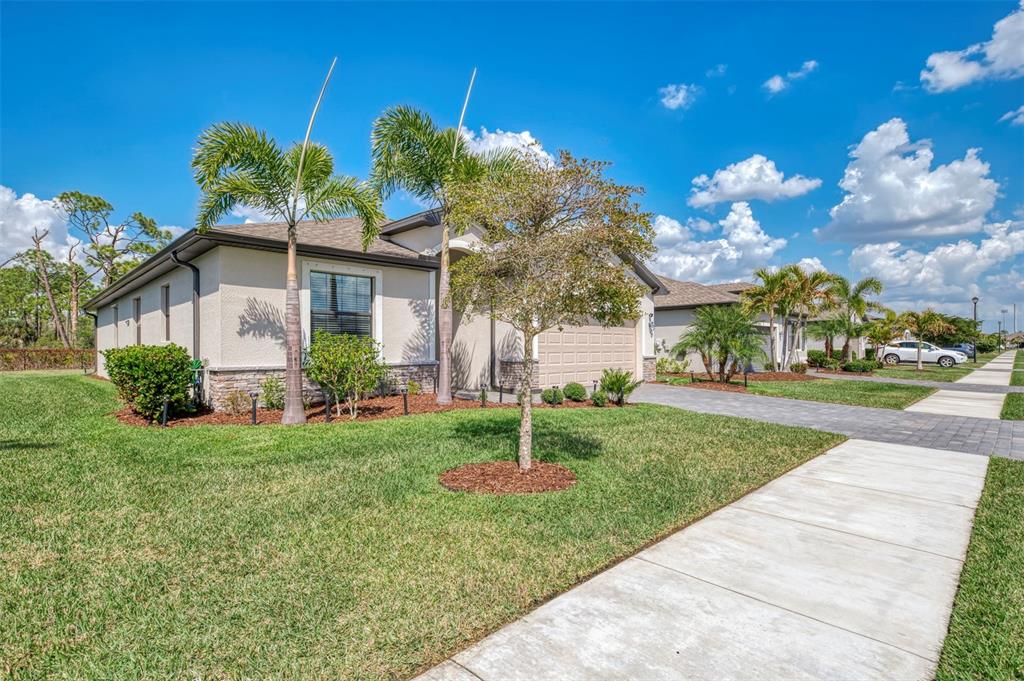 A single-story house with a paved driveway, palm trees, and a manicured lawn — 15896 HONEYSUCKLE STREET, PORT CHARLOTTE, FL