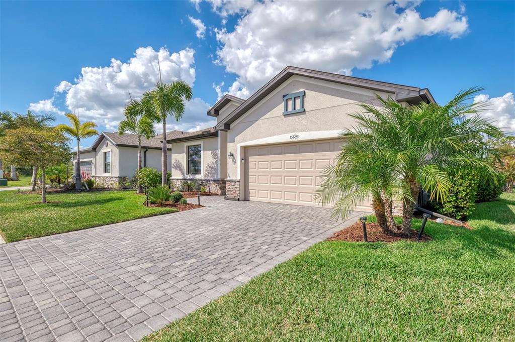 A single-story house with a paved driveway, a two-car garage, and palm trees — 15896 HONEYSUCKLE STREET, PORT CHARLOTTE, FL