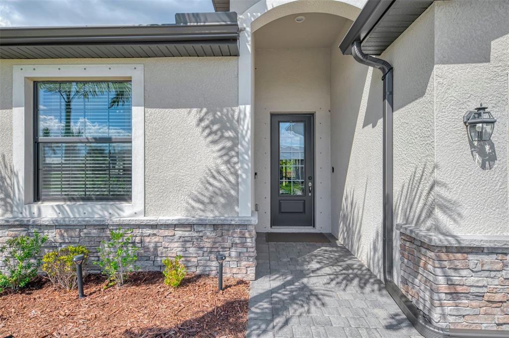 A front entryway features a dark door, stone veneer siding, and a paved walkway — 15896 HONEYSUCKLE STREET, PORT CHARLOTTE, FL