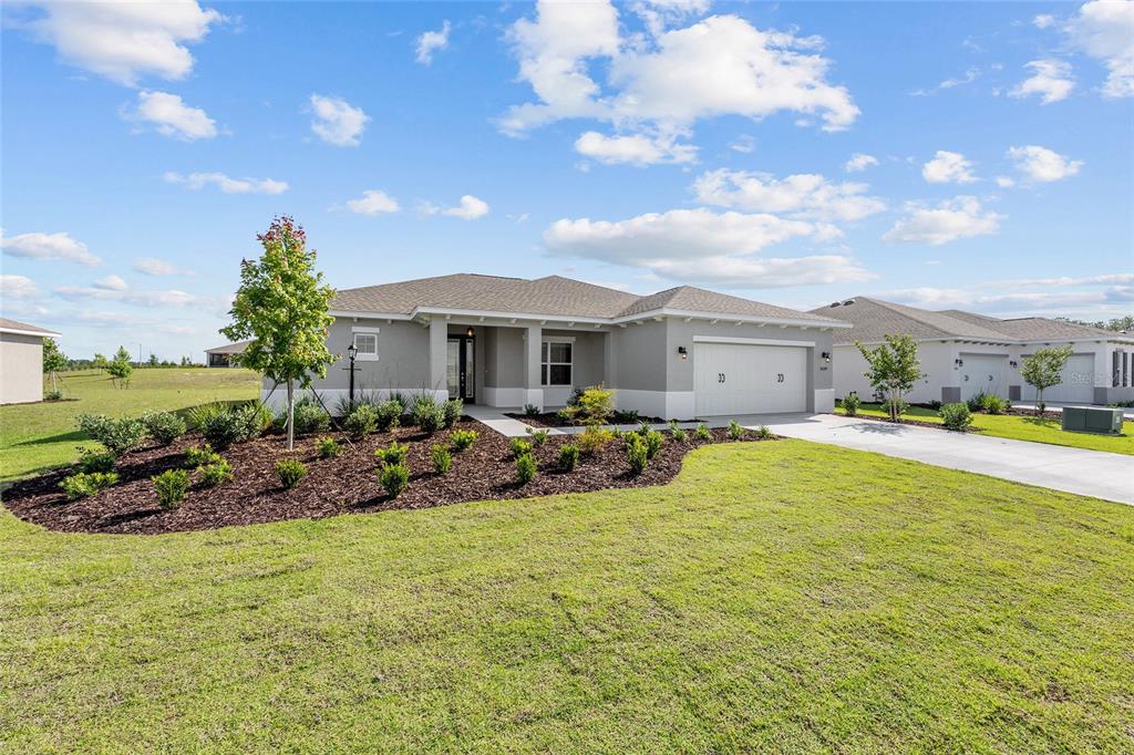 A single-story suburban house with a gray stucco exterior, a two-car garage, and landscaped yard — 10649 SW 101ST LANE ROAD, OCALA, FL