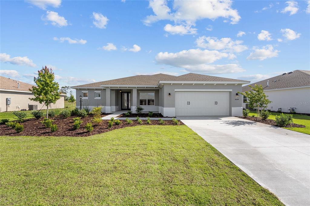 A single-story house with a gray exterior, a two-car garage, and a landscaped front yard — 10649 SW 101ST LANE ROAD, OCALA, FL