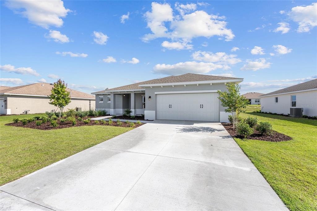 A single-story house with a two-car garage, concrete driveway, and landscaped front yard — 10649 SW 101ST LANE ROAD, OCALA, FL