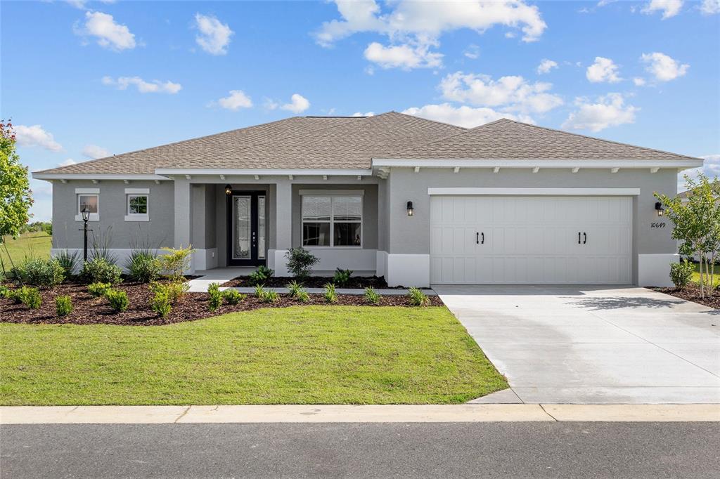 A single-story gray house with a two-car garage and a landscaped front yard — 10649 SW 101ST LANE ROAD, OCALA, FL