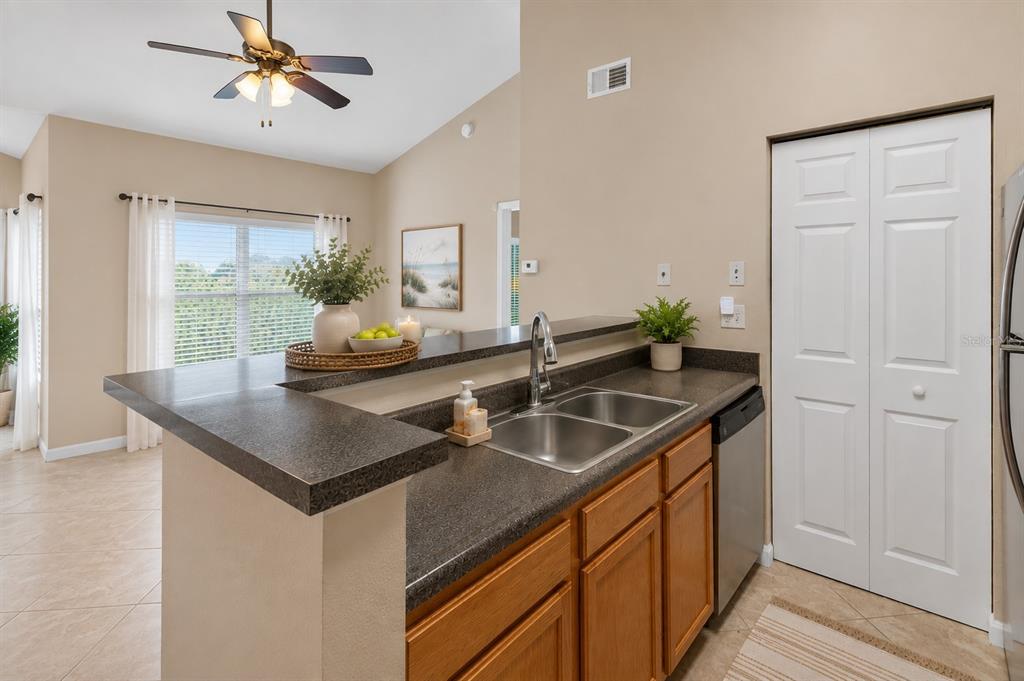 A kitchen with a double-basin sink, dark countertops, wood cabinets, and a breakfast bar — 10764 70TH AVENUE UNIT 1304, SEMINOLE, FL