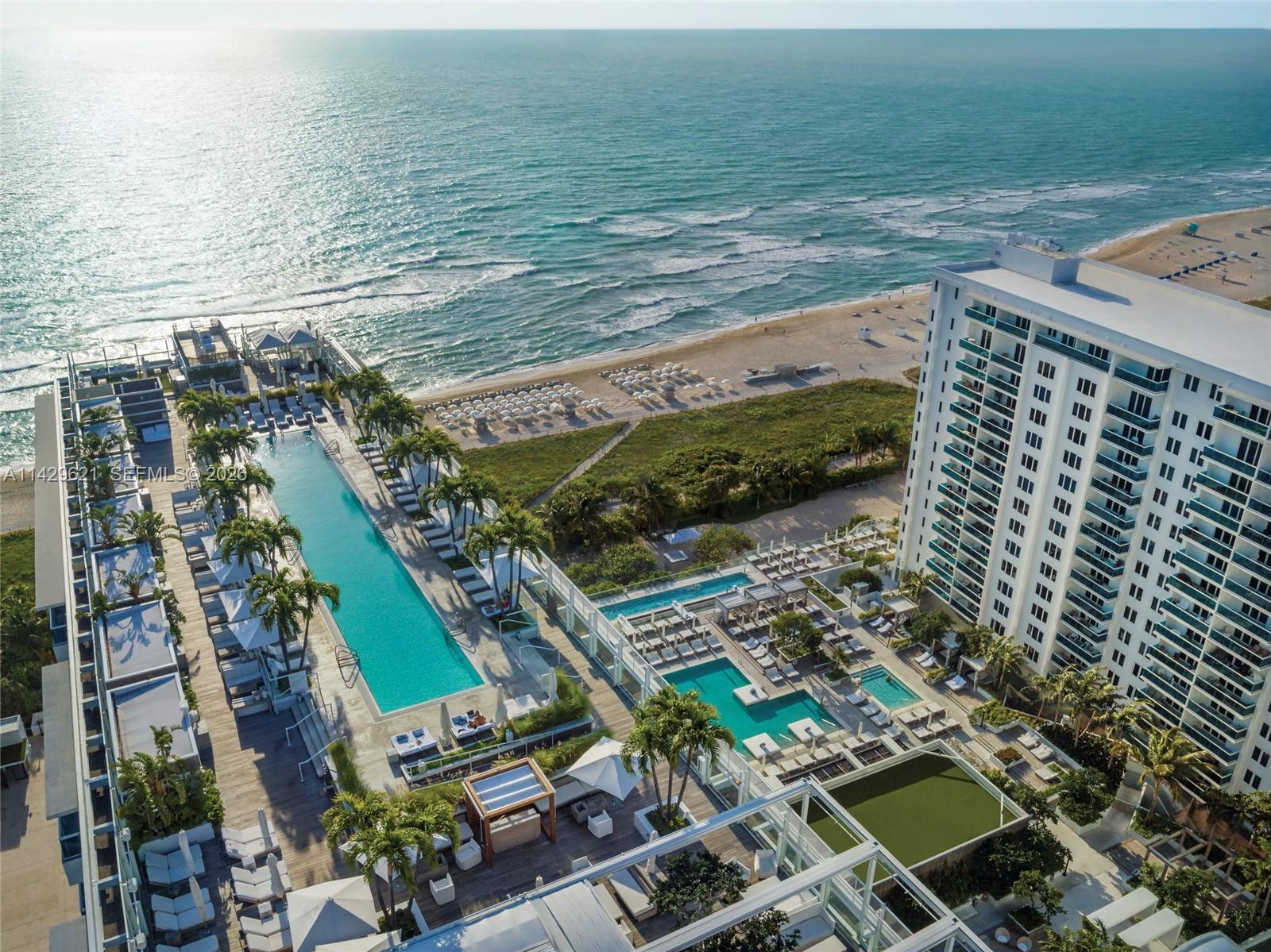 A modern kitchen with white cabinets and stainless steel appliances opens into a dining area — 102 24th St # 1108, Miami Beach FL 33139, MIAMI BEACH, FL