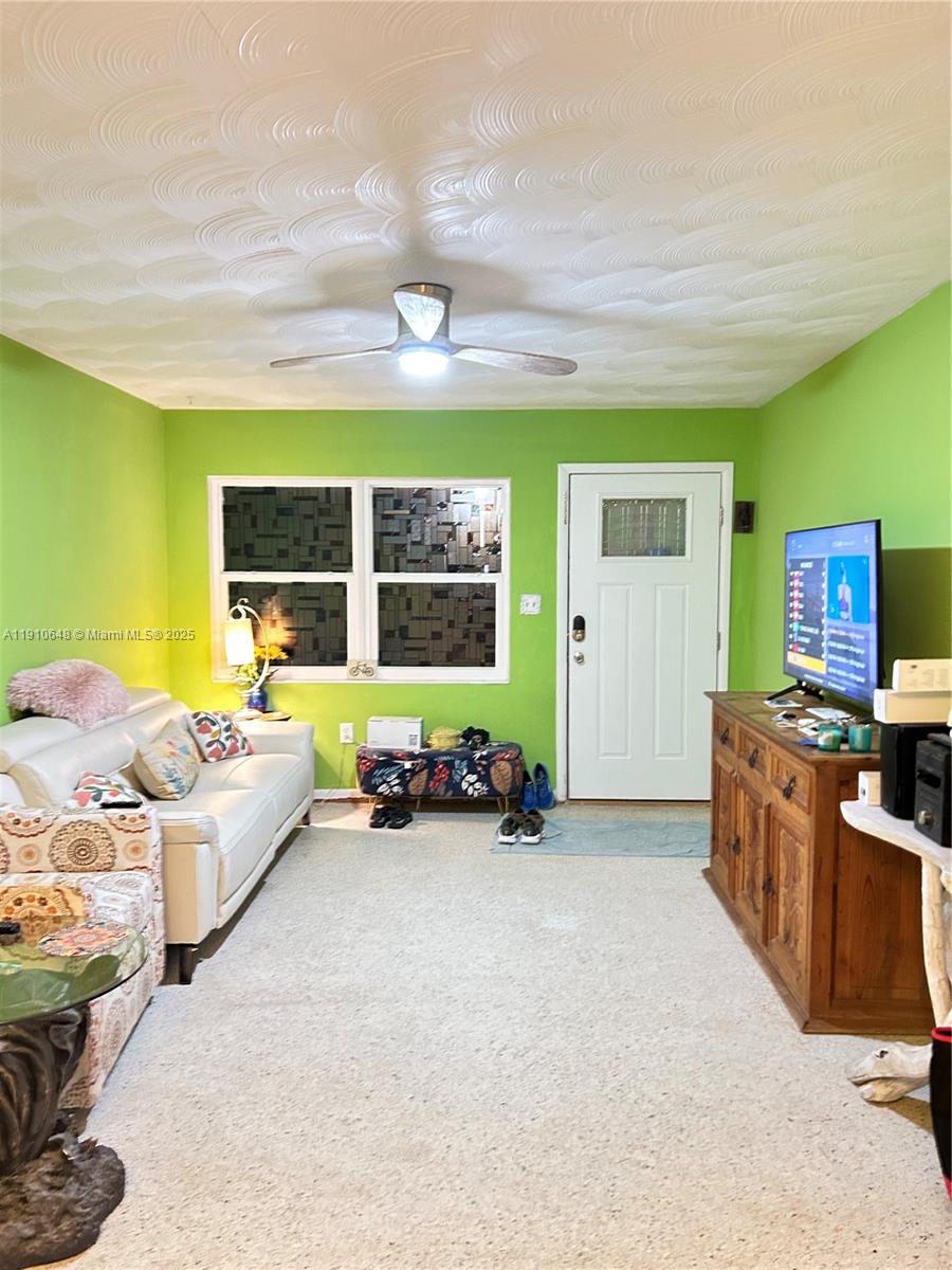 A living room features bright green walls, a textured ceiling, a ceiling fan, and carpet — 118 Bougainvillea Dr, Rockledge FL 32955, ROCKLEDGE, FL