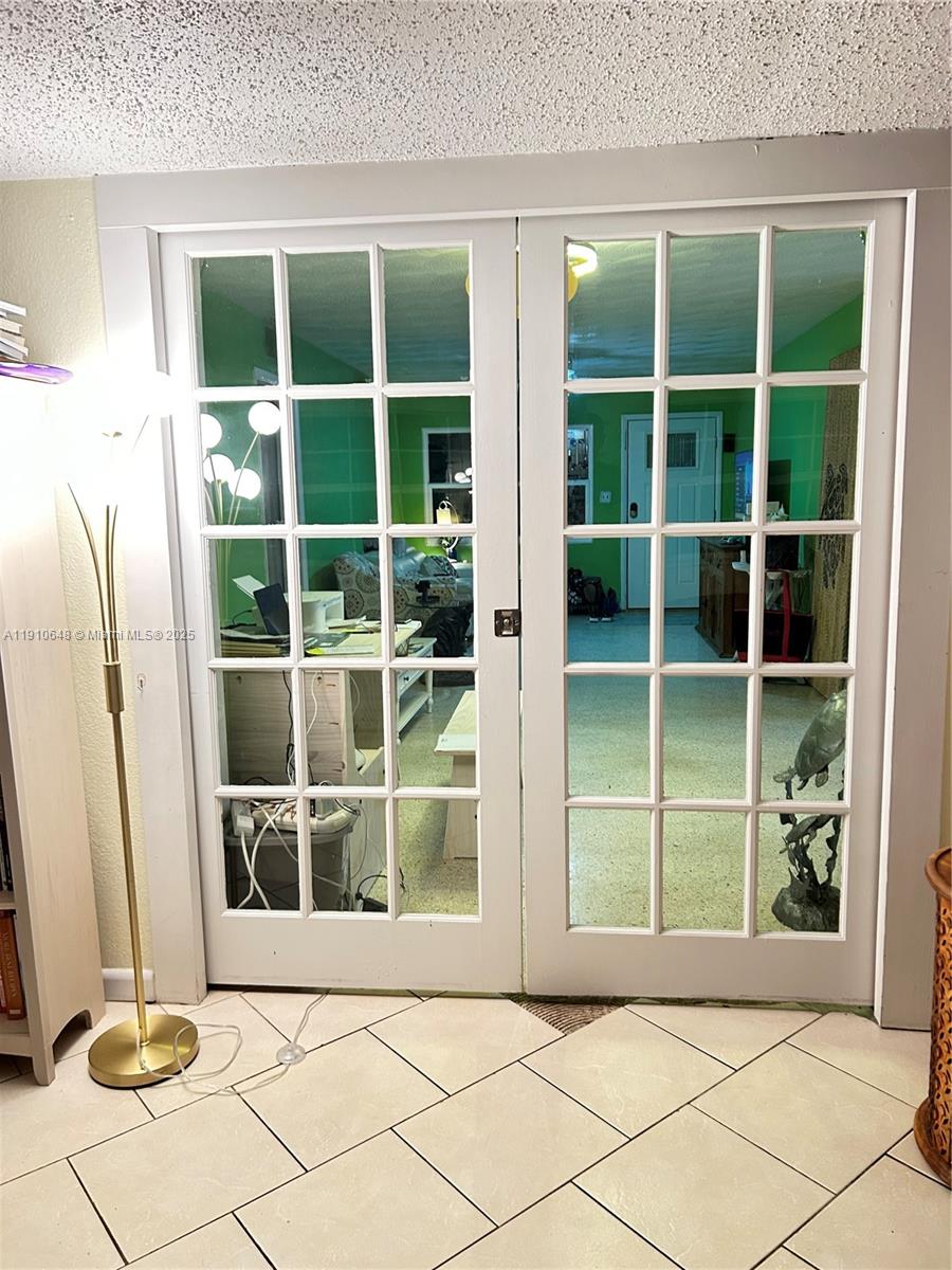A set of white French doors with glass panes separates two rooms with tiled floors — 118 Bougainvillea Dr, Rockledge FL 32955, ROCKLEDGE, FL