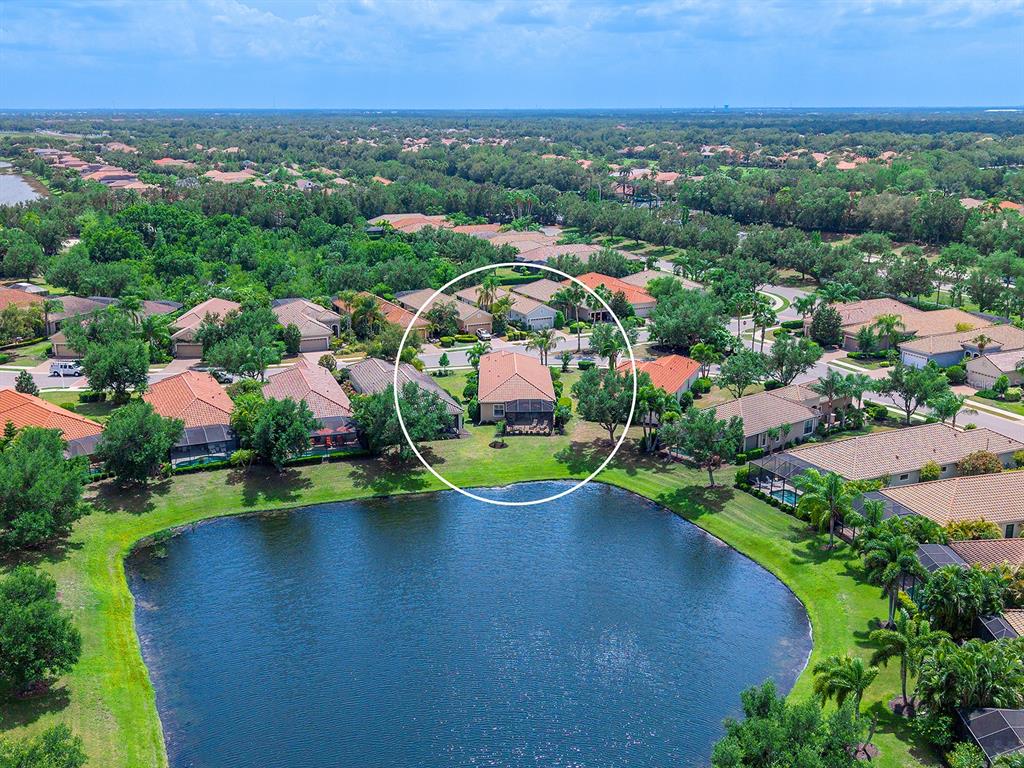 An aerial view shows a suburban house with a screened patio overlooking a lake — 7263 BELLEISLE GLEN, LAKEWOOD RANCH, FL