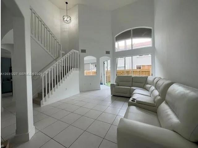 A bright living room features white tile floors, a staircase, and a large sectional sofa — 8042 NW 114th Pl, Doral FL 33178, DORAL, FL