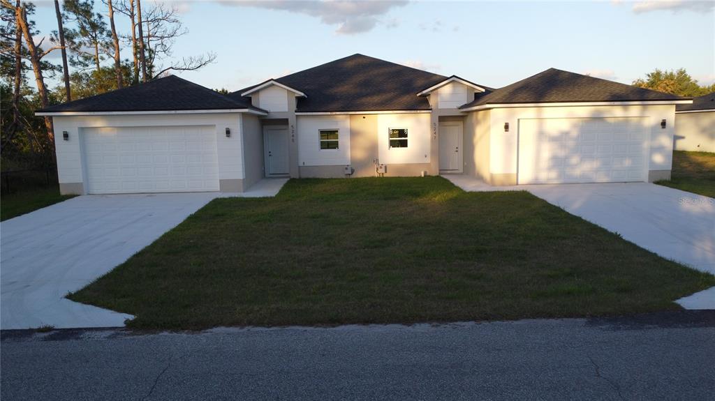 A duplex house with two garages, white siding, and a shared front lawn — 5245 PEBBLE BEACH DRIVE, SEBRING, FL