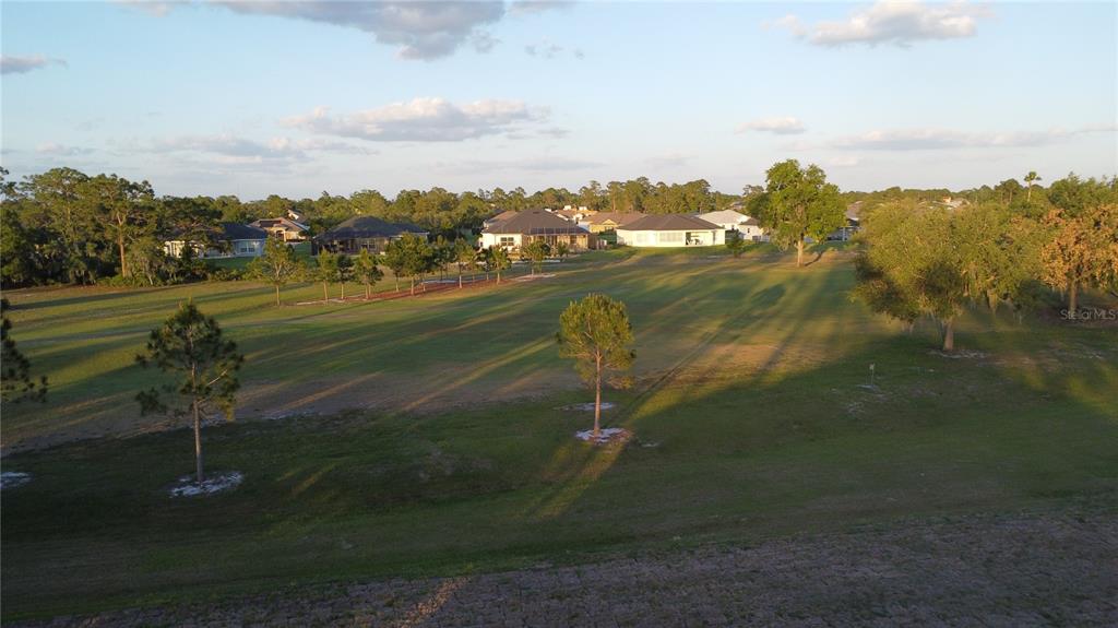 An elevated view of a grassy field with scattered trees and houses in the background — 5245 PEBBLE BEACH DRIVE, SEBRING, FL