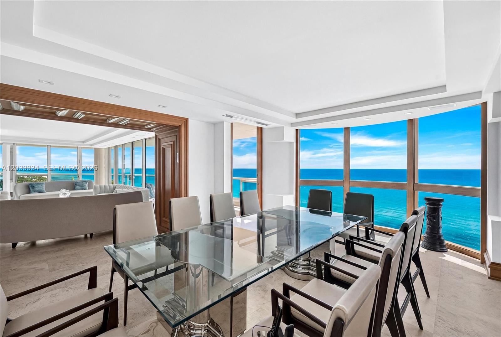 A dining room with a glass table overlooks the ocean through floor-to-ceiling windows — 5025 Collins Ave # 1105, Miami Beach FL 33140, MIAMI BEACH, FL