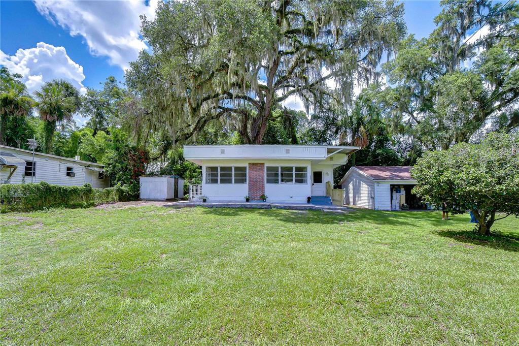 A single-story house with white siding and a brick chimney sits on a grassy lot — 39200 FIBELKORN ROAD, ZEPHYRHILLS, FL