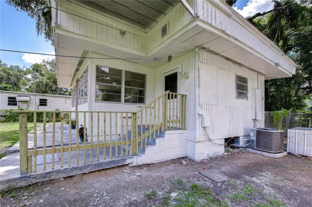 The exterior of a white house features a wooden deck, stairs, and an air conditioning unit — 39200 FIBELKORN ROAD, ZEPHYRHILLS, FL