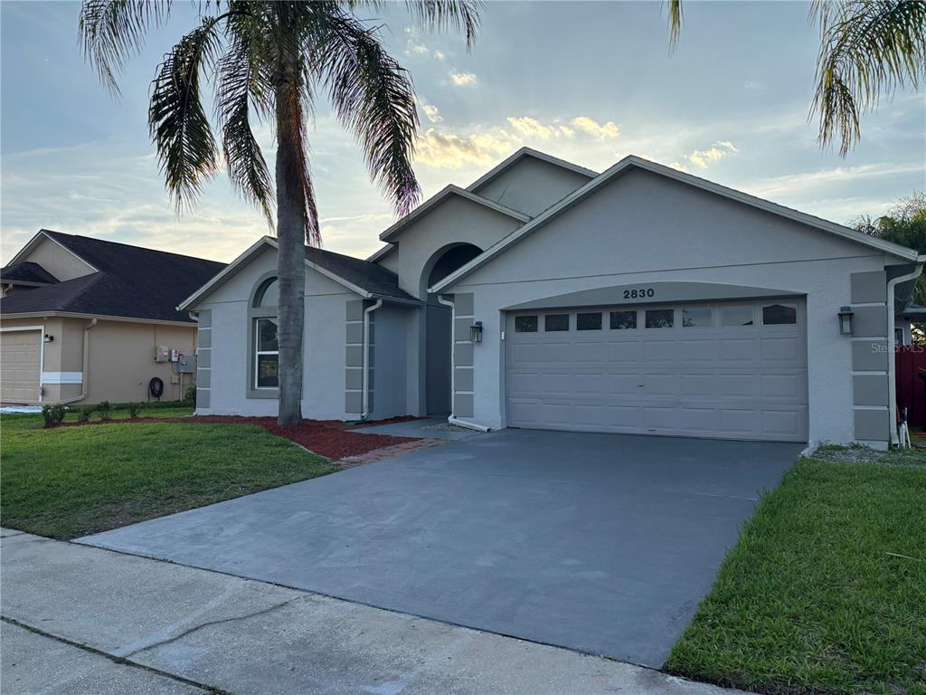 A single-story house with a gray stucco exterior, a two-car garage, and a palm tree — 2830 STRAND CIRCLE, OVIEDO, FL