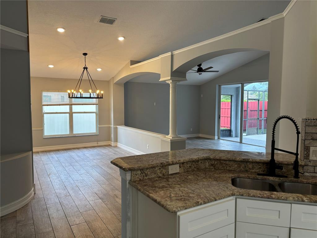 A kitchen with granite countertops overlooks a dining area and a living room with columns — 2830 STRAND CIRCLE, OVIEDO, FL