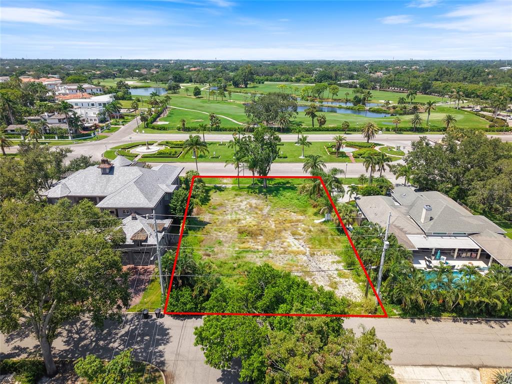 An aerial view shows a vacant rectangular lot situated between two houses near a golf course — 409 SNELL ISLE BOULEVARD NE, ST PETERSBURG, FL